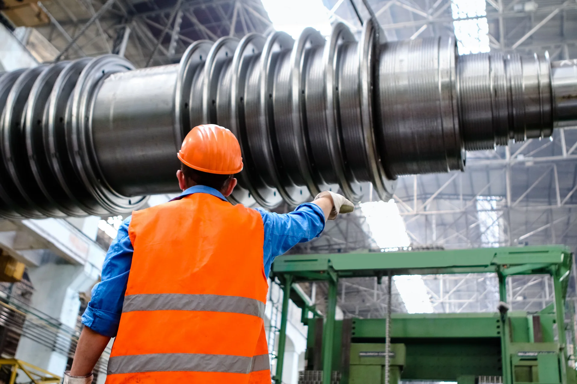 Industrial worker wearing a hard hat and high-visibility vest beside machinery